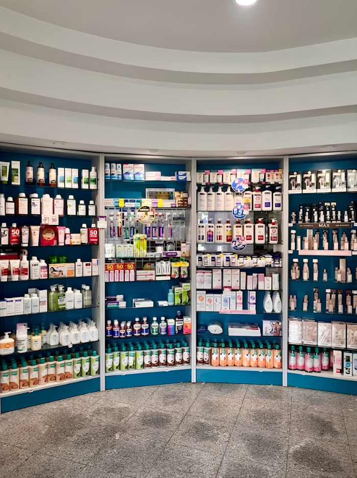 Prateleiras de uma farmácia com produtos de saúde e medicamentos organizados.